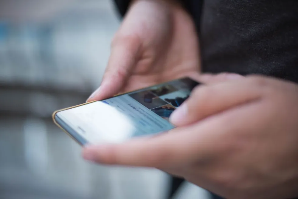 Elindeki akıllı telefonu kullanan bir kişi